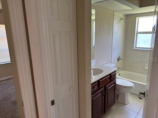 full bathroom with tiled shower / bath, toilet, tile floors, and vanity