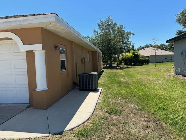 view of side of property featuring a garage, central AC unit, and a lawn