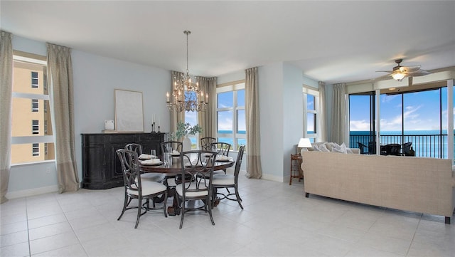 tiled dining area featuring ceiling fan with notable chandelier, plenty of natural light, and a water view