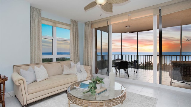 living room with ceiling fan, a water view, and light tile floors