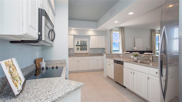 kitchen with white cabinets, stainless steel appliances, and light tile floors