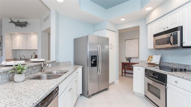 kitchen with light stone counters, white cabinetry, stainless steel appliances, light tile floors, and sink