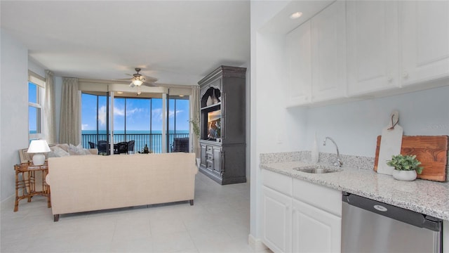 kitchen with a water view, ceiling fan, white cabinets, sink, and stainless steel dishwasher