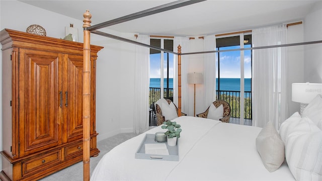 carpeted bedroom featuring floor to ceiling windows, multiple windows, a water view, and access to outside