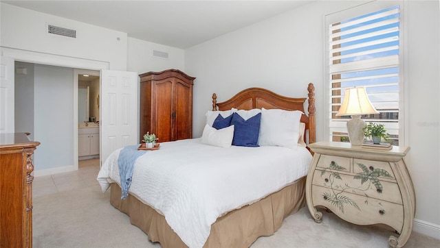 bedroom featuring light carpet and ensuite bath