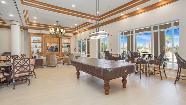 rec room with pool table, a high ceiling, a notable chandelier, light wood-type flooring, and ornamental molding