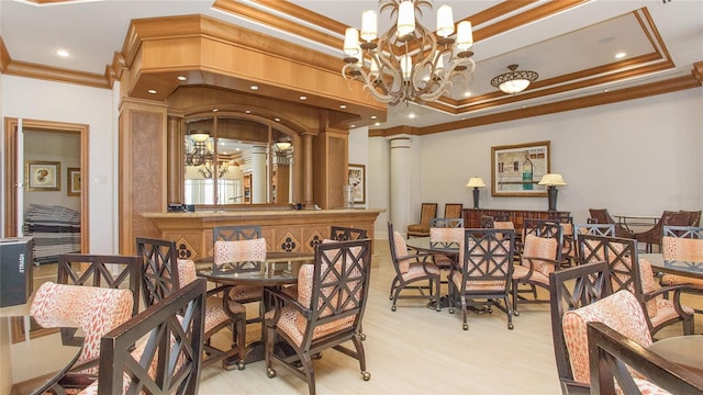 dining space with a tray ceiling, light wood-type flooring, a chandelier, and ornamental molding