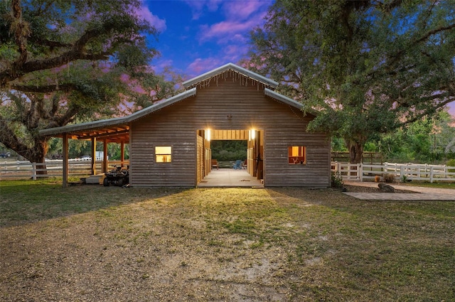 back house at dusk featuring a yard and a patio area