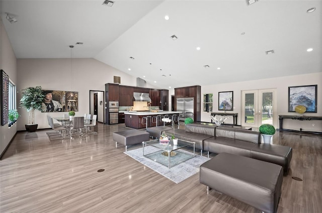 living room with high vaulted ceiling, french doors, and light wood-type flooring