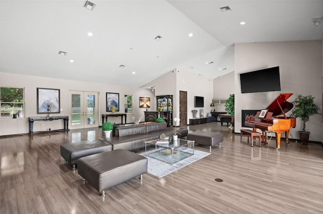 living room with high vaulted ceiling, french doors, and light hardwood / wood-style floors