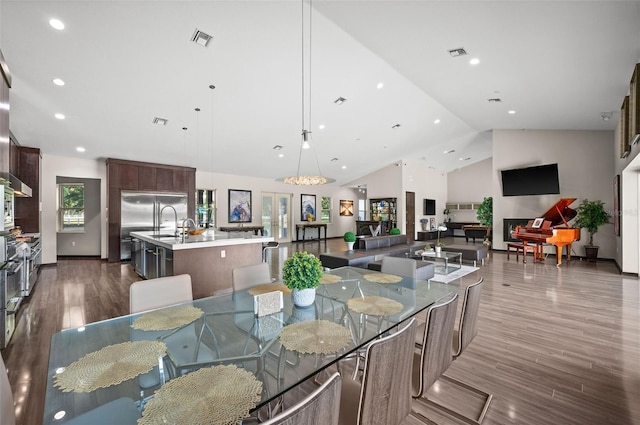 dining area featuring high vaulted ceiling and hardwood / wood-style floors