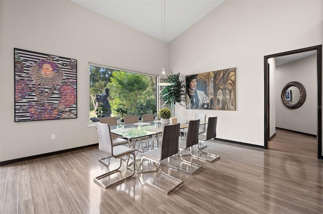 dining space with wood-type flooring and high vaulted ceiling