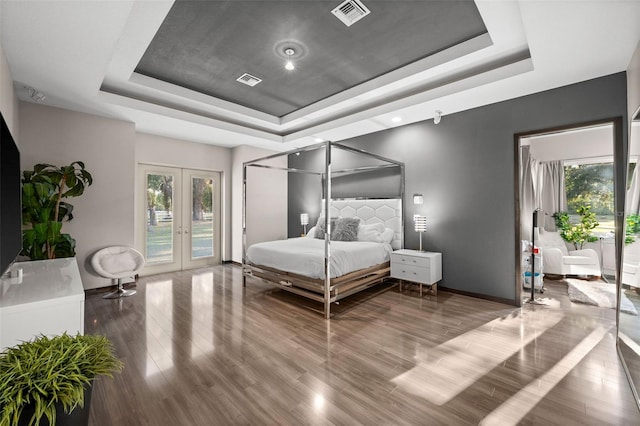 bedroom featuring dark hardwood / wood-style floors, french doors, and a tray ceiling