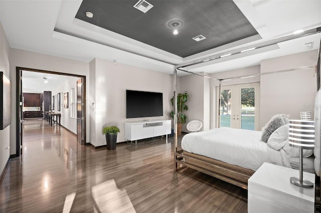 bedroom with french doors, dark hardwood / wood-style floors, and a raised ceiling