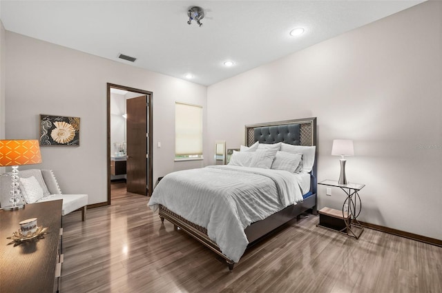 bedroom with ensuite bath and dark hardwood / wood-style flooring