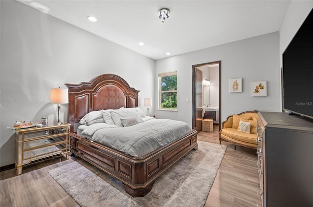 bedroom featuring ensuite bath and hardwood / wood-style flooring