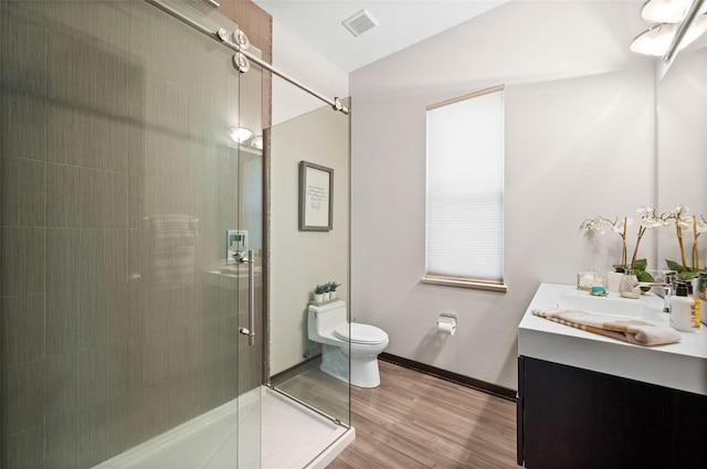 bathroom with hardwood / wood-style flooring, an enclosed shower, toilet, and vanity with extensive cabinet space