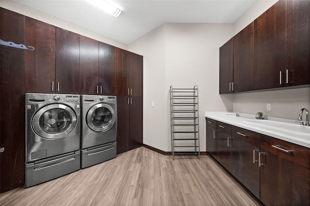 washroom with light hardwood / wood-style flooring, cabinets, sink, and washer and dryer