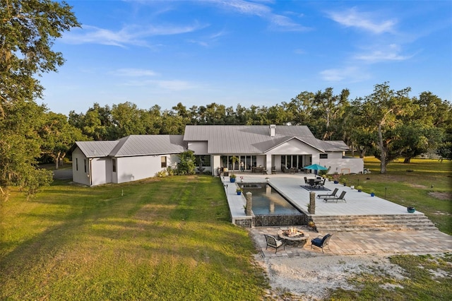 back of house featuring a patio, an outdoor fire pit, and a lawn