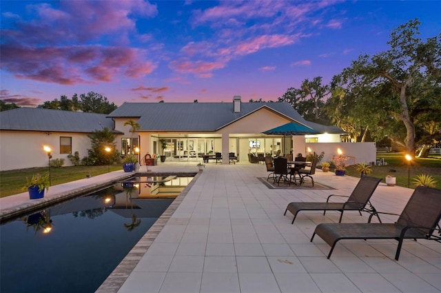 pool at dusk featuring a patio