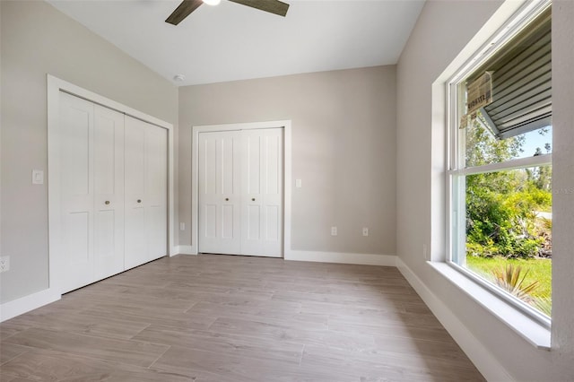 unfurnished bedroom featuring ceiling fan and two closets