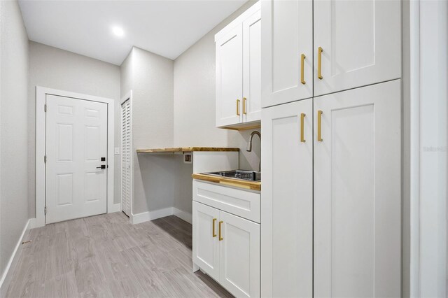 laundry room featuring washer hookup, light hardwood / wood-style floors, and cabinets