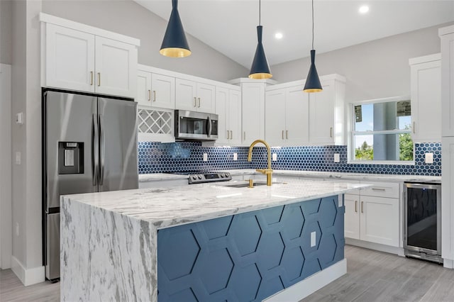 kitchen with beverage cooler, stainless steel appliances, sink, hanging light fixtures, and light stone counters