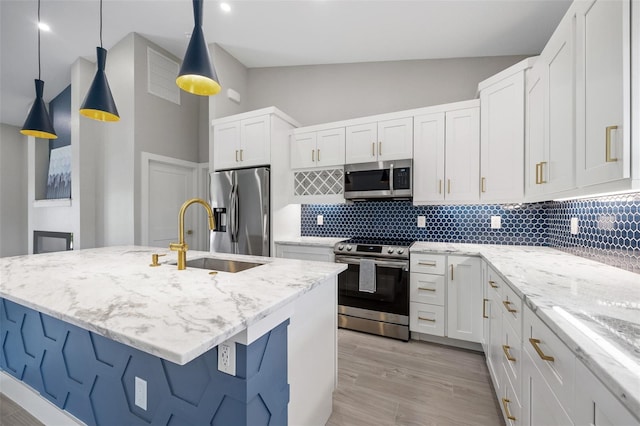 kitchen featuring pendant lighting, white cabinetry, stainless steel appliances, an island with sink, and sink