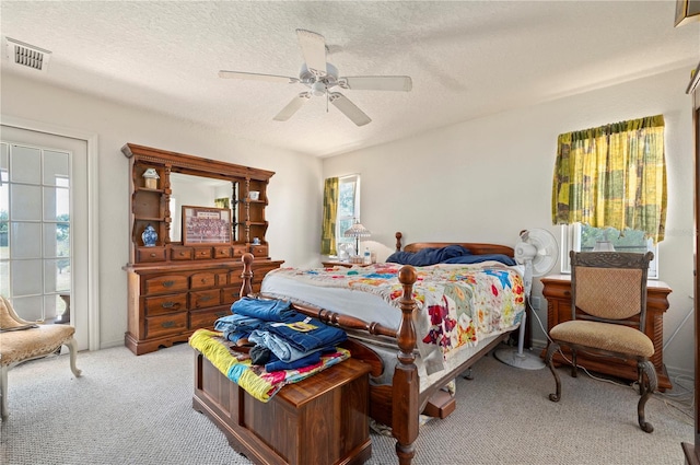 bedroom featuring light carpet, ceiling fan, and a textured ceiling