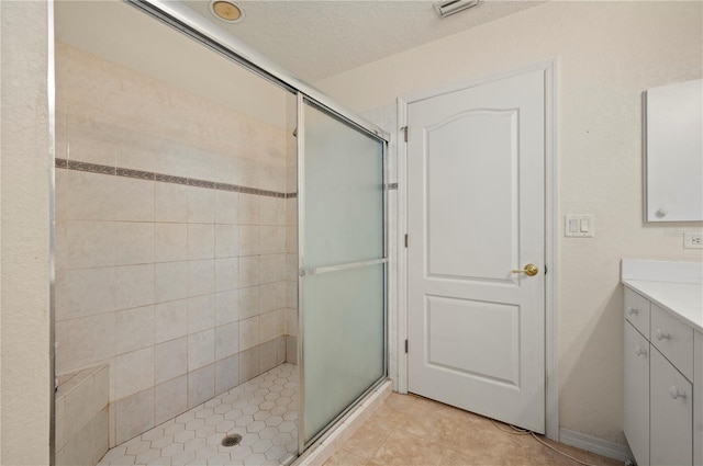 bathroom featuring a shower with door, tile floors, vanity, and a textured ceiling