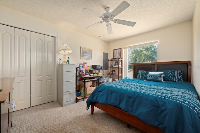 carpeted bedroom featuring a closet, ceiling fan, and a textured ceiling