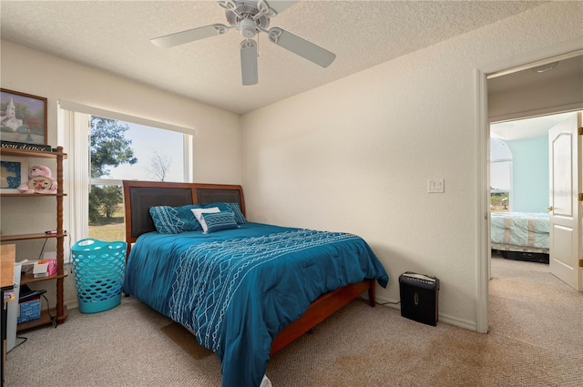 bedroom with light colored carpet, ceiling fan, and a textured ceiling