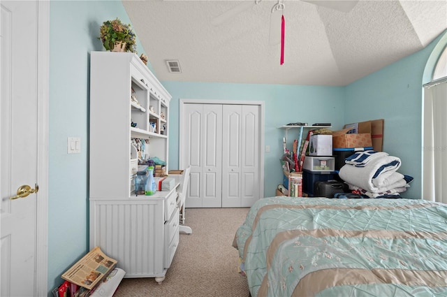 bedroom featuring a closet, ceiling fan, a textured ceiling, light colored carpet, and lofted ceiling