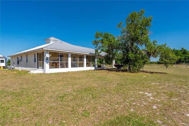 rear view of property with a yard, a sunroom, and central AC