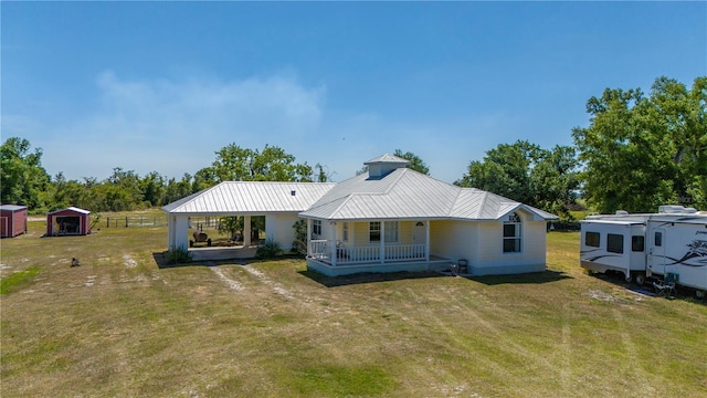 rear view of property with a lawn, a shed, and a porch