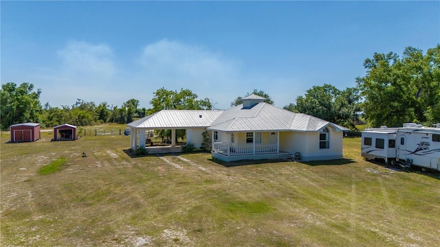 rear view of property with covered porch, a lawn, and a storage unit