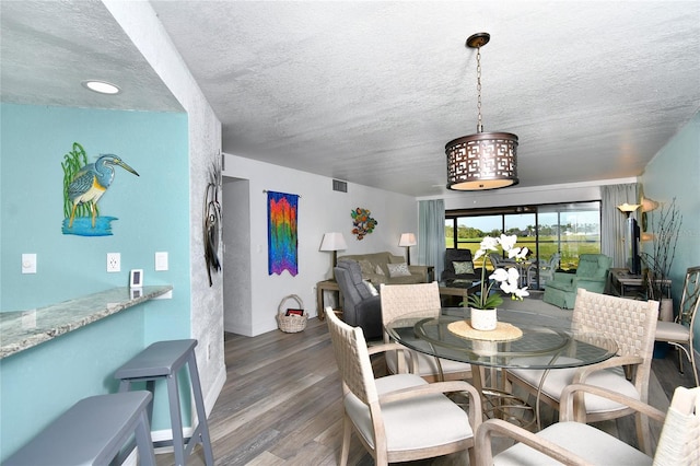 dining area featuring dark wood-type flooring and a textured ceiling