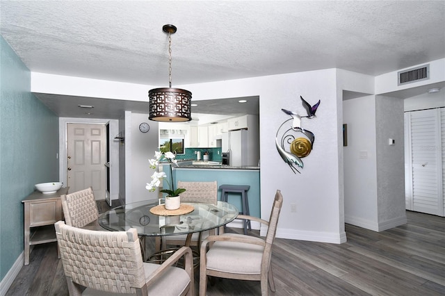 dining space with dark hardwood / wood-style flooring and a textured ceiling