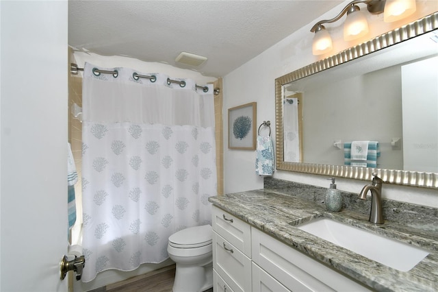 bathroom with a textured ceiling, hardwood / wood-style floors, vanity, and toilet