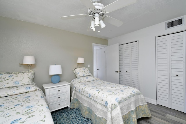 bedroom featuring multiple closets, ceiling fan, and dark wood-type flooring