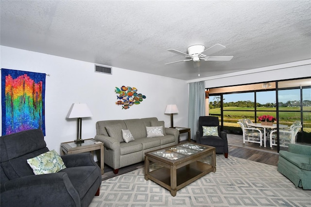 living room featuring a textured ceiling, hardwood / wood-style floors, and ceiling fan