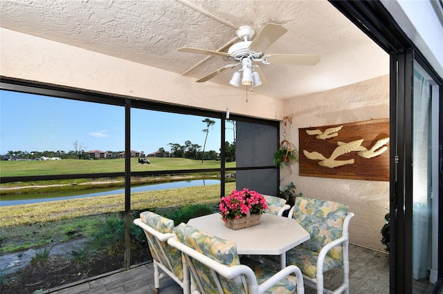 sunroom featuring ceiling fan and a water view