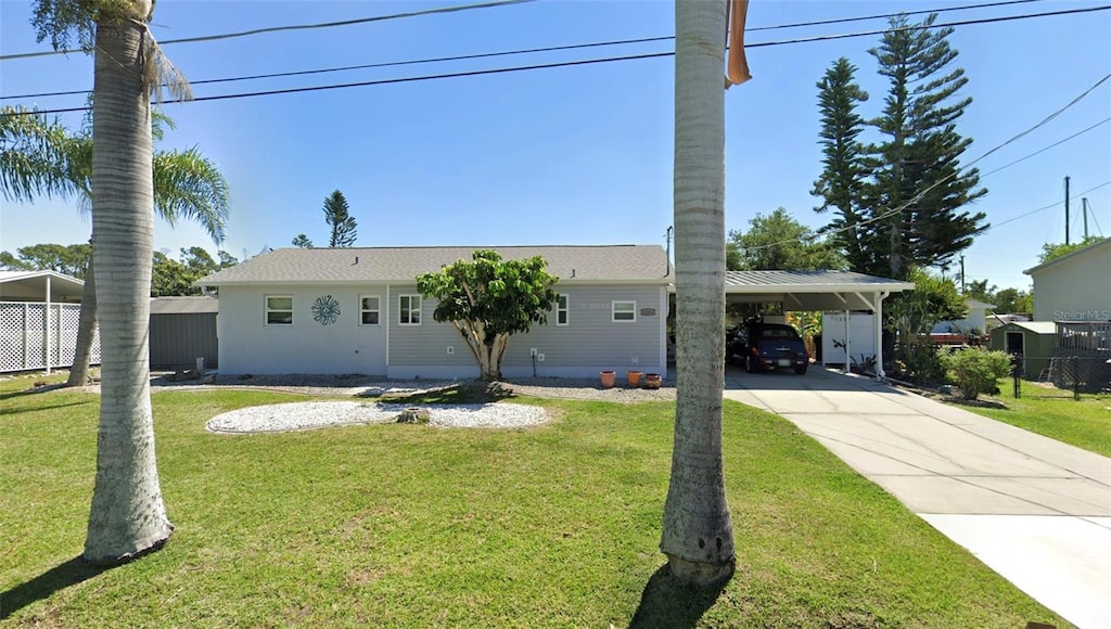 ranch-style home with an attached carport, concrete driveway, and a front lawn