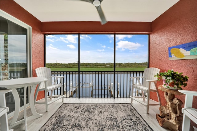 sunroom / solarium featuring a water view and ceiling fan