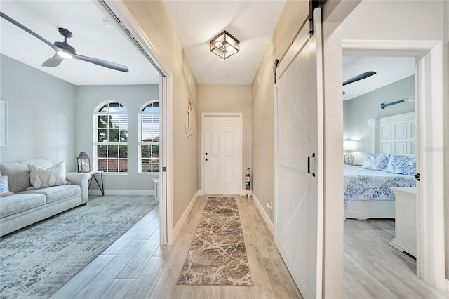 interior space featuring a barn door, ceiling fan, and light wood-type flooring