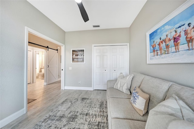 living room featuring a barn door, ceiling fan, and hardwood / wood-style floors