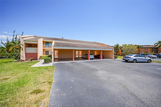 view of front of home featuring a carport, a front lawn, and a balcony