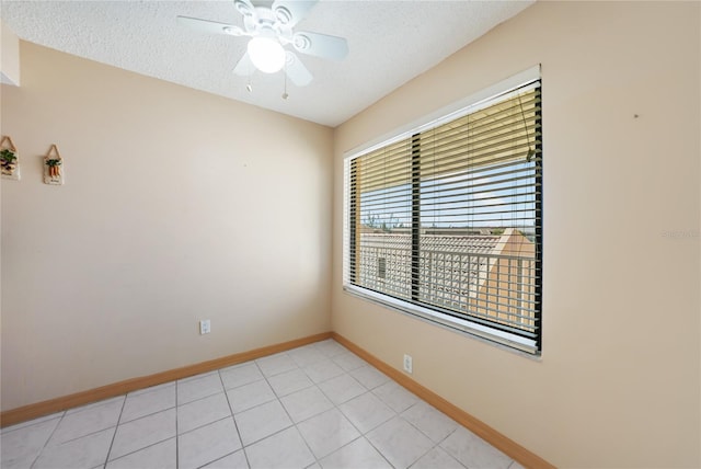 tiled empty room featuring ceiling fan and a textured ceiling