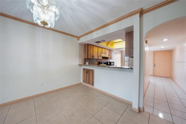 kitchen with crown molding, an inviting chandelier, a textured ceiling, and light tile flooring