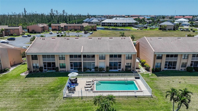 back of property with a yard and a fenced in pool